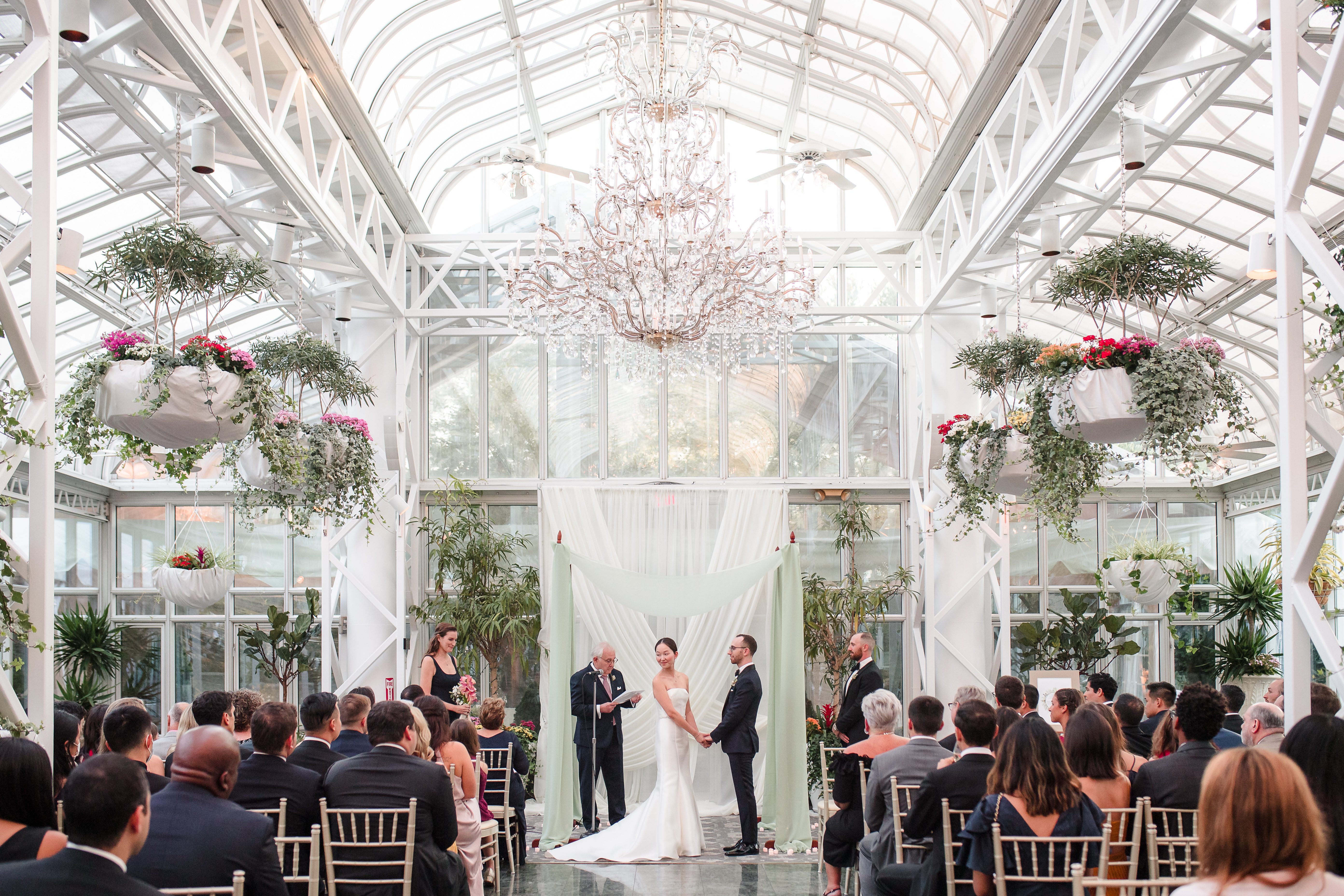 Wide ceremony shot inside greenhouse venue